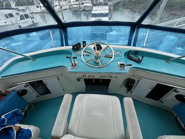 Slide: The Image of 1974 Tollycraft 40 Tri-Cabin helm with blue dashboard and steering wheel, overlooking marina. - 18
