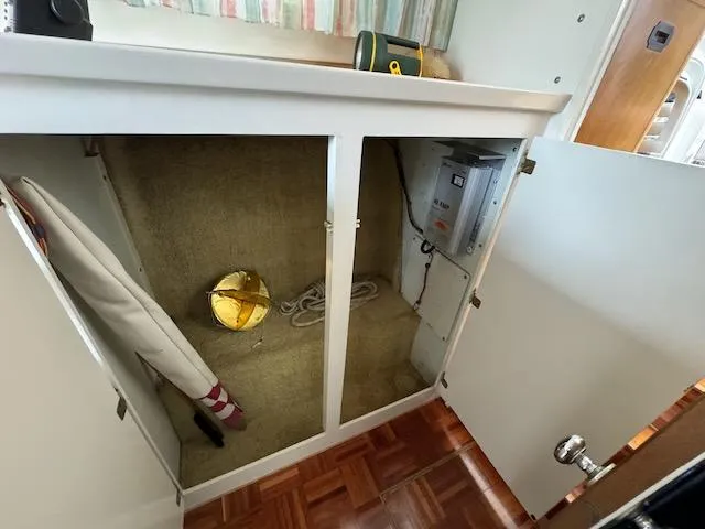 Slide: The Image of Open cabinet in 1974 Tollycraft 40 Tri-Cabin with storage items and electrical panel. - 21