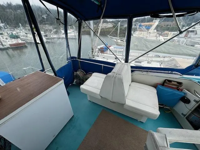 Slide: The Image of 1974 Tollycraft 40 Tri-Cabin interior with white seating and marina view. - 23