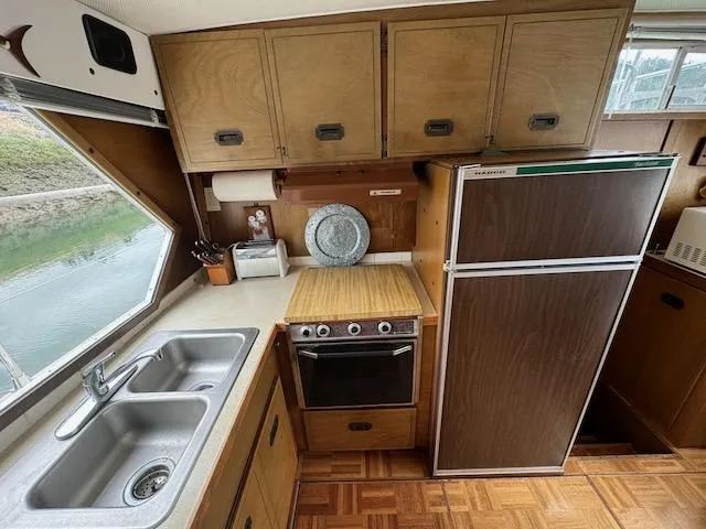 Slide: The Image of 1974 Tollycraft 40 Tri-Cabin kitchen with wood cabinets, stove, and double sink. - 27