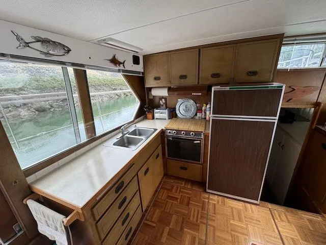 Slide: The Image of 1974 Tollycraft 40 Tri-Cabin kitchen with wood cabinets, stove, and large window view. - 28