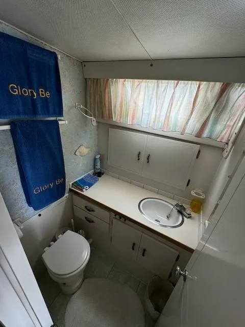 Slide: The Image of 1974 Tollycraft 40 Tri-Cabin bathroom with sink, toilet, and "Glory Be" towels. - 33