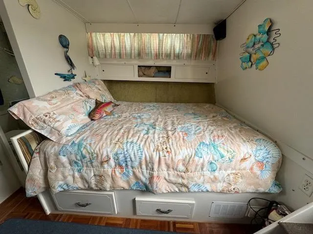 Slide: The Image of Cozy bedroom in 1974 Tollycraft 40 Tri-Cabin with seashell-themed bedding and wall decor. - 7