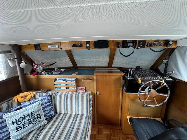 Slide: The Image of Interior of 1974 Tollycraft 40 Tri-Cabin with helm, striped sofa, and nautical decor. - 9