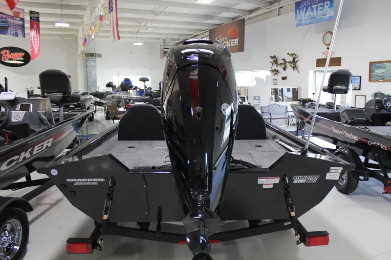Slide: The Image of 2025 Tracker Pro Team 175 boat displayed in showroom, rear view with motor. - 17