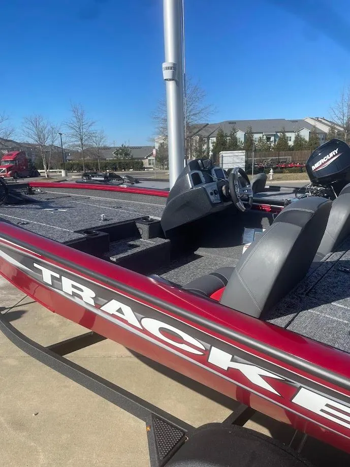 Slide: The Image of 2025 Tracker Pro Team 175 boat with red detailing, parked outdoors on a sunny day. - 2