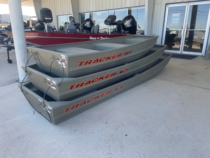 Slide: The Image of 2025 Tracker Grizzly 1236 Utility boats stacked outside dealership. - 2