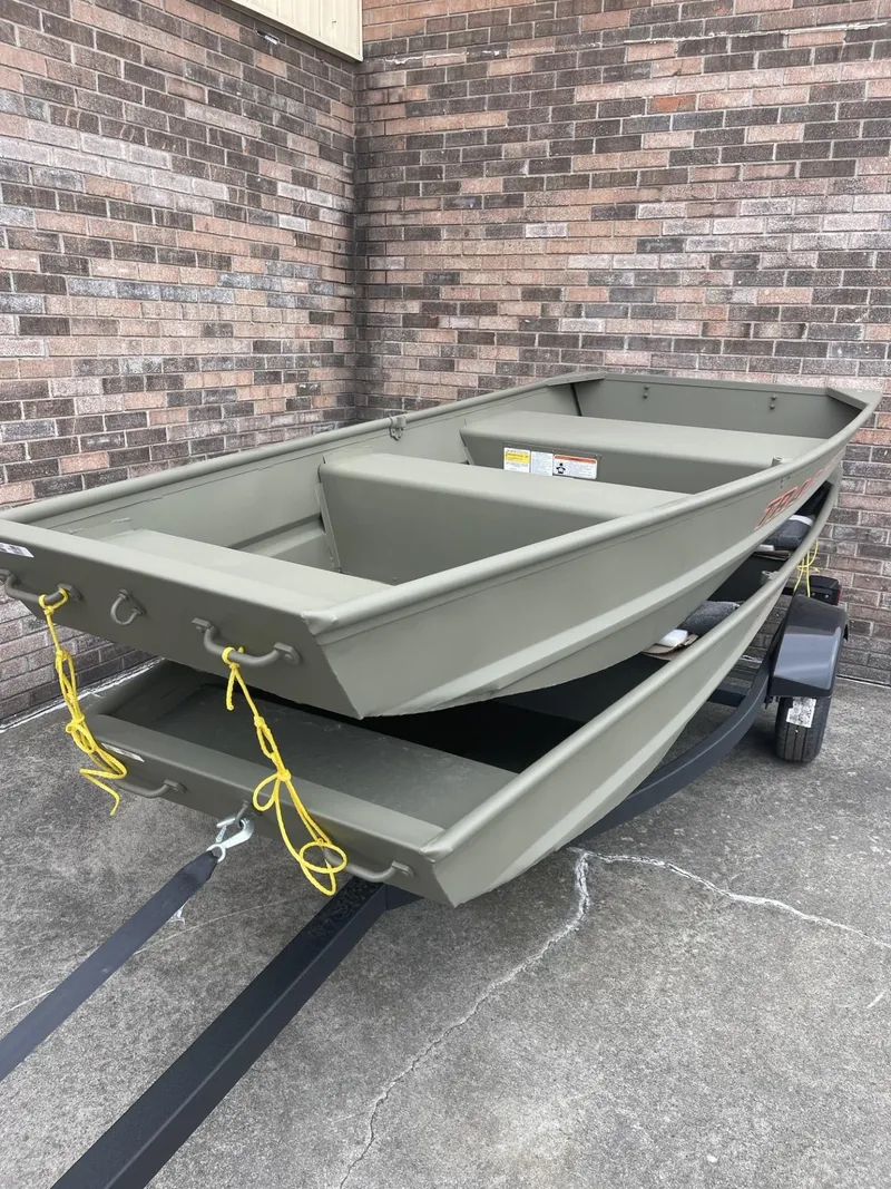 Slide: The Image of 2025 Tracker Grizzly 1036 Utility boats stacked on trailer, against brick wall. - 5