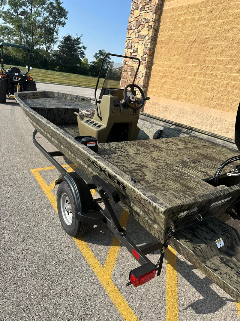 Slide: The Image of 2025 Tracker Grizzly 1860 CC boat on trailer, camo design, parked outdoors. - 2