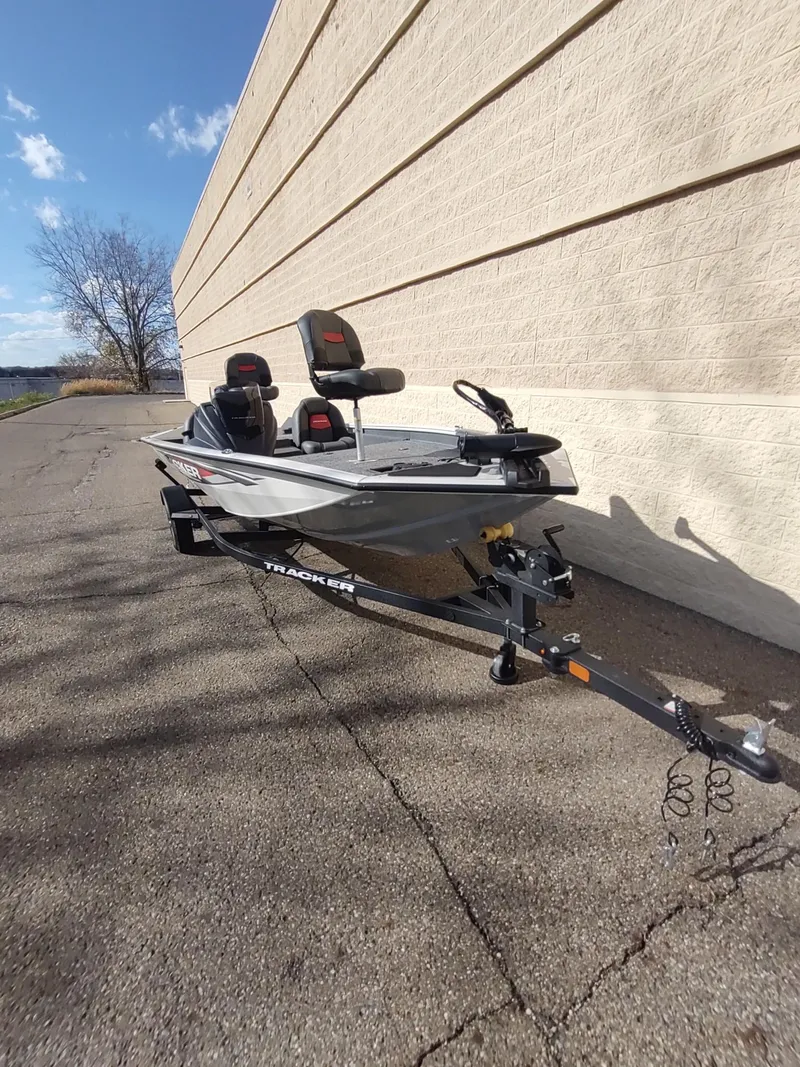 Slide: The Image of 2025 Tracker Pro Team 175 boat on trailer, parked beside a beige wall. - 4