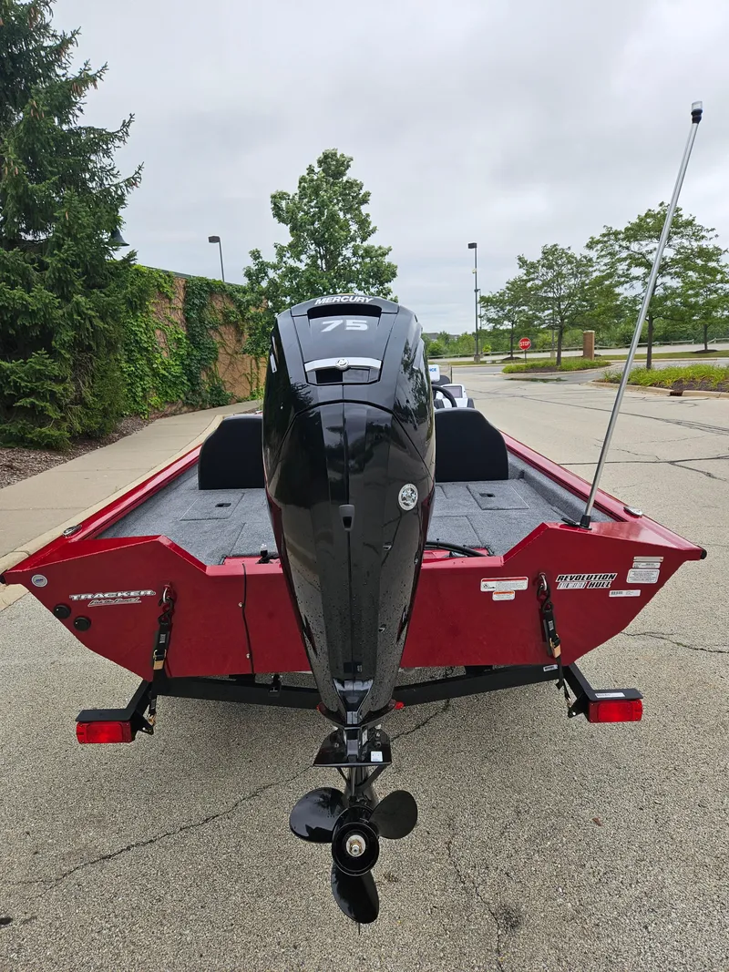 Slide: The Image of 2025 Tracker Pro Team 175 boat, red exterior, rear view with motor, parked outdoors. - 3