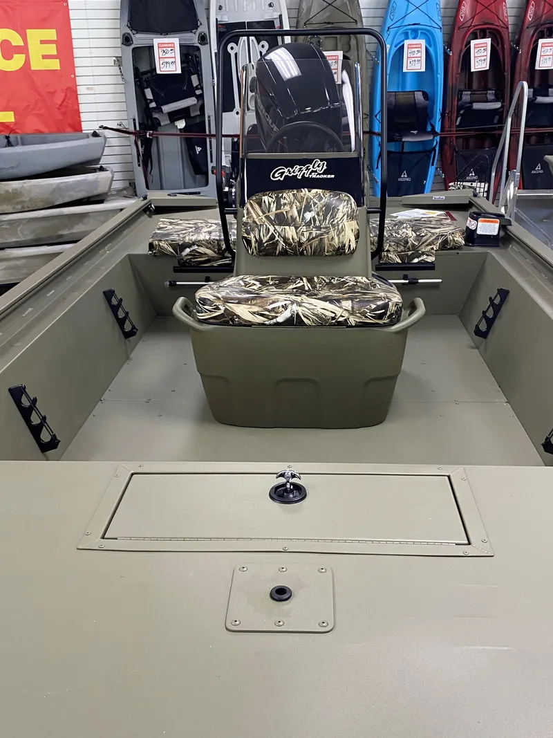 Slide: The Image of 2025 Tracker Grizzly 1860 CC boat interior with camo seating, showroom display. - 3