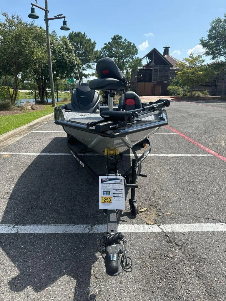Slide: The Image of 2025 Tracker Pro Team 175 boat parked in sunny lot with trees and building. - 3
