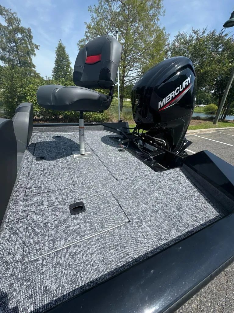 Slide: The Image of 2025 Tracker Pro Team 175 boat with Mercury engine and seating, parked outdoors. - 6