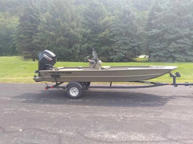 The Image of 2025 Tracker Grizzly 1860 CC boat on trailer, parked on asphalt with trees in background. - 0