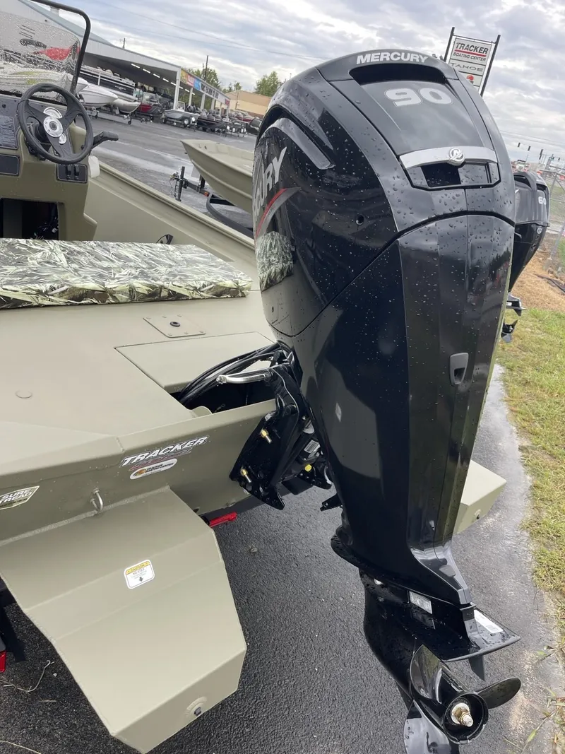 Slide: The Image of 2025 Tracker Grizzly 1860 CC boat with Mercury 90 outboard motor, parked on wet pavement. - 3