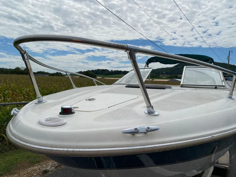 Slide: The Image of 2000 Bayliner 2352 Capri DX/LX boat with stainless steel railings under a cloudy sky. - 35