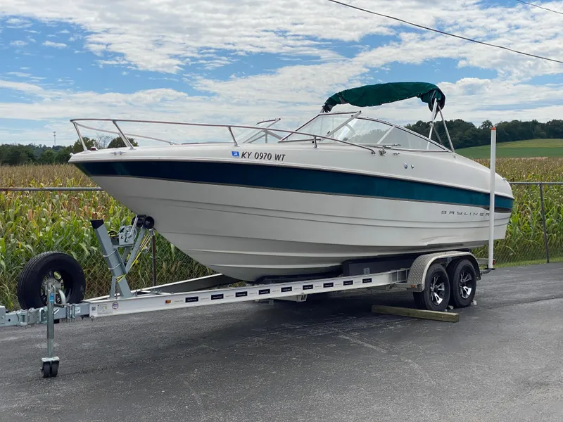 Slide: The Image of 2000 Bayliner 2352 Capri DX/LX boat on trailer, parked outdoors under cloudy sky. - 37