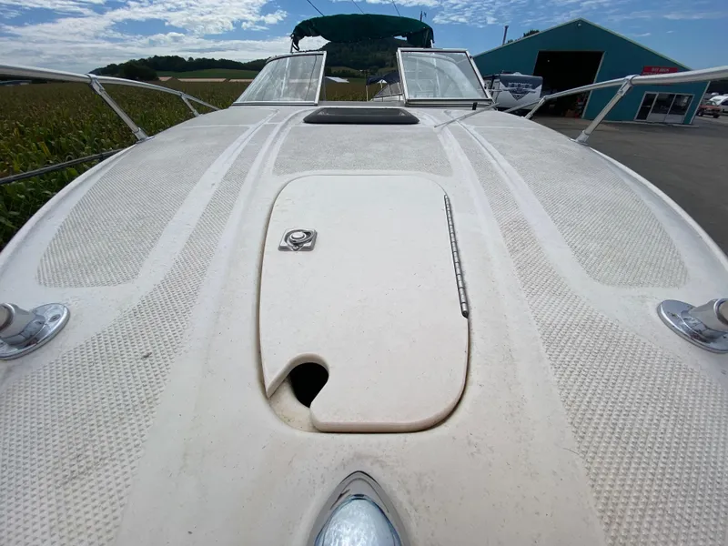 Slide: The Image of 2000 Bayliner 2352 Capri DX/LX boat deck with hatch, docked near a blue building. - 8