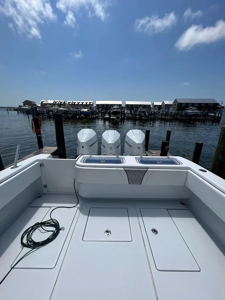 Slide: The Image of 2021 Contender 35 ST boat docked with triple engines, clear sky, and waterfront view. - 6