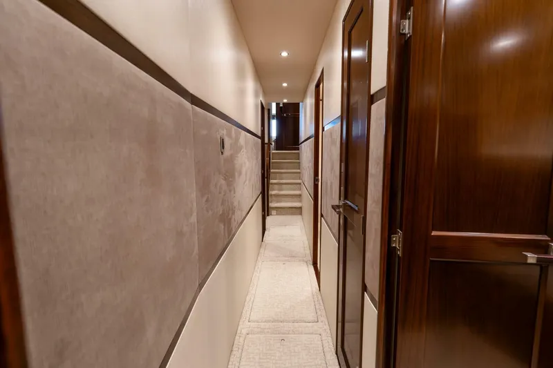 Slide: The Image of Interior hallway of 2015 Viking 76 Convertible yacht with wooden doors and carpeted floor. - 32
