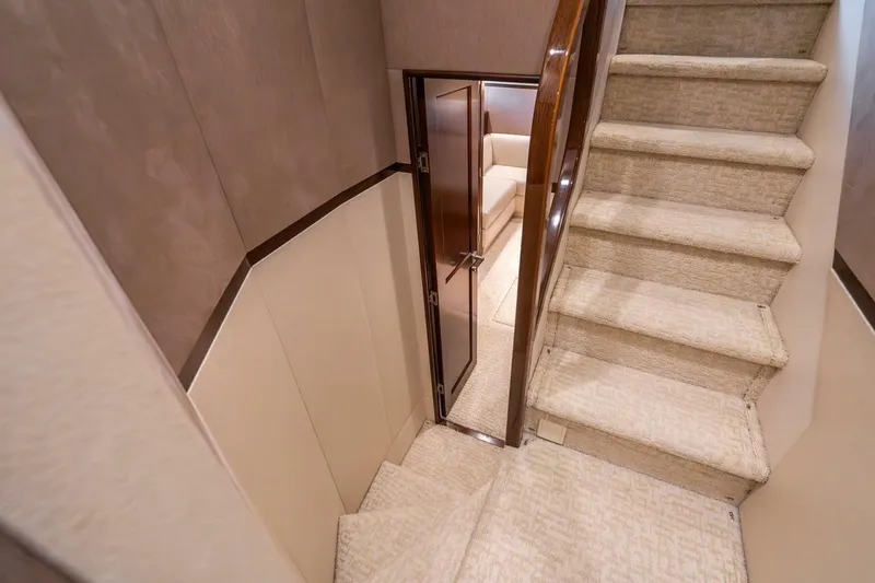 Slide: The Image of Interior staircase of 2015 Viking 76 Convertible yacht, featuring carpeted steps and wooden accents. - 38
