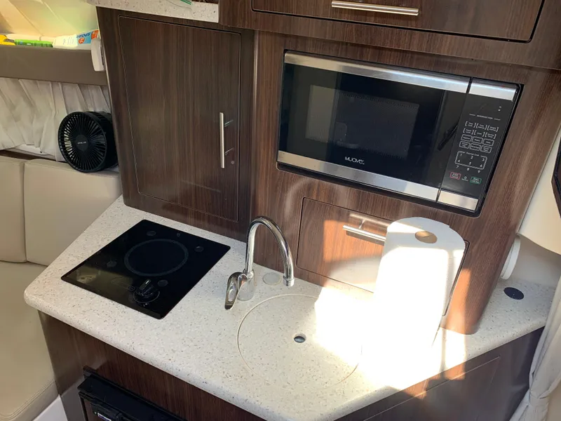 Slide: The Image of 2018 Regal 28 Express boat kitchen with microwave, stovetop, and sink. - 21