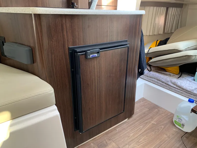 Slide: The Image of 2018 Regal 28 Express interior with wood paneling and compact fridge. - 25