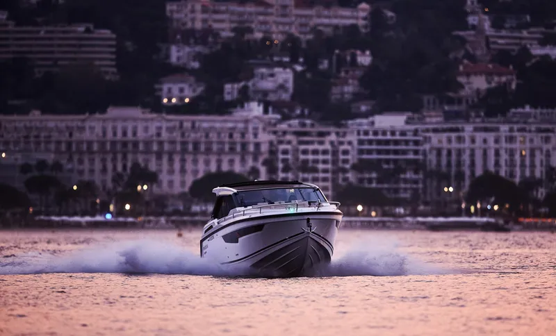 Slide: The Image of 2024 Skamander Sorrento boat cruising on water at sunset with cityscape background. - 1