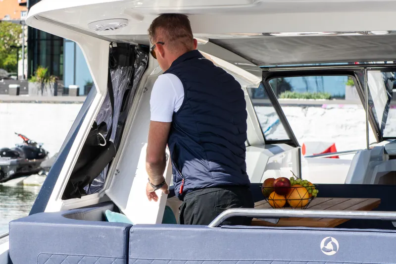 Slide: The Image of Man on 2024 Skamander Sorrento boat, arranging items near a table with fruit basket. - 45