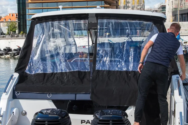 Slide: The Image of 2024 Skamander Sorrento boat with protective cover in a marina setting. - 46