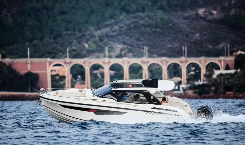 Slide: The Image of 2024 Skamander Sorrento boat cruising on water with scenic bridge and forested background. - 5