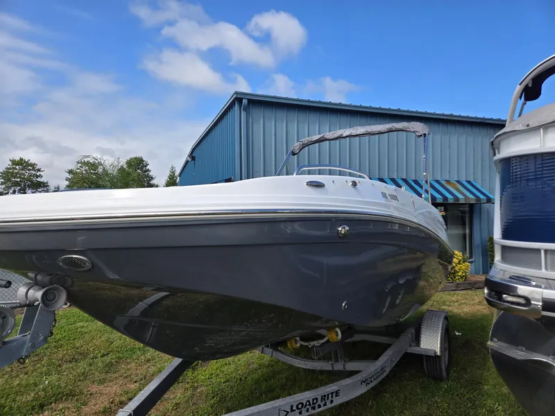 Slide: The Image of 2025 Hurricane SunDeck Sport 192 RL OB boat on trailer, parked near blue building. - 4