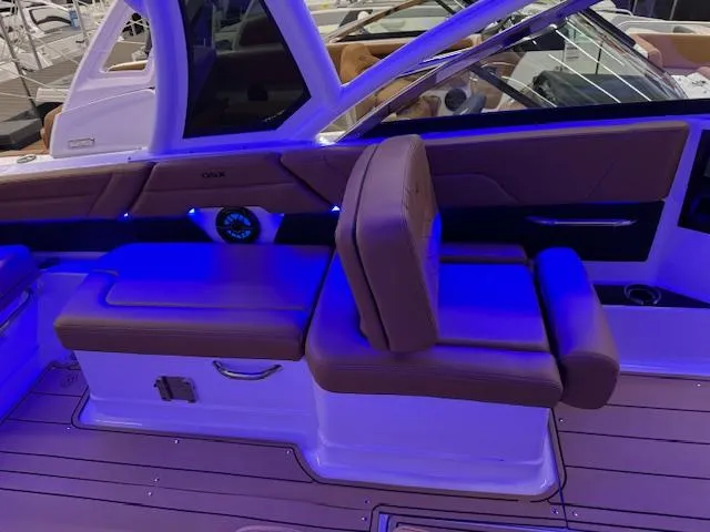 Slide: The Image of 2025 Chaparral 310 OSX boat interior with blue LED lighting and cushioned seating. - 16