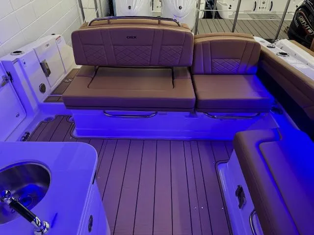 Slide: The Image of 2025 Chaparral 310 OSX boat interior with brown seating and blue LED lighting. - 21