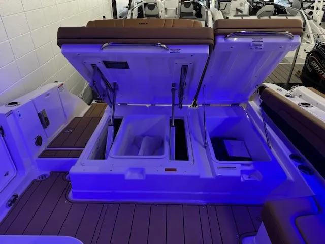 Slide: The Image of 2025 Chaparral 310 OSX boat with open storage compartments, illuminated in blue light. - 22