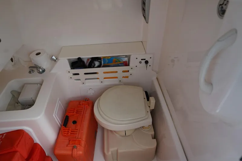 Slide: The Image of Compact boat bathroom with toilet, storage, and safety equipment on a 2011 Everglades 295. - 23