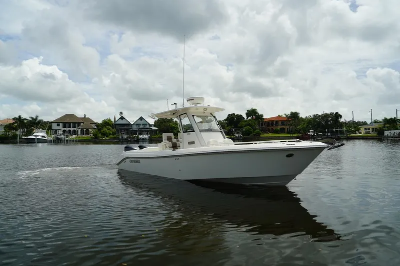 Slide: The Image of 2011 Everglades 295 boat cruising on a calm lake with houses in the background. - 4