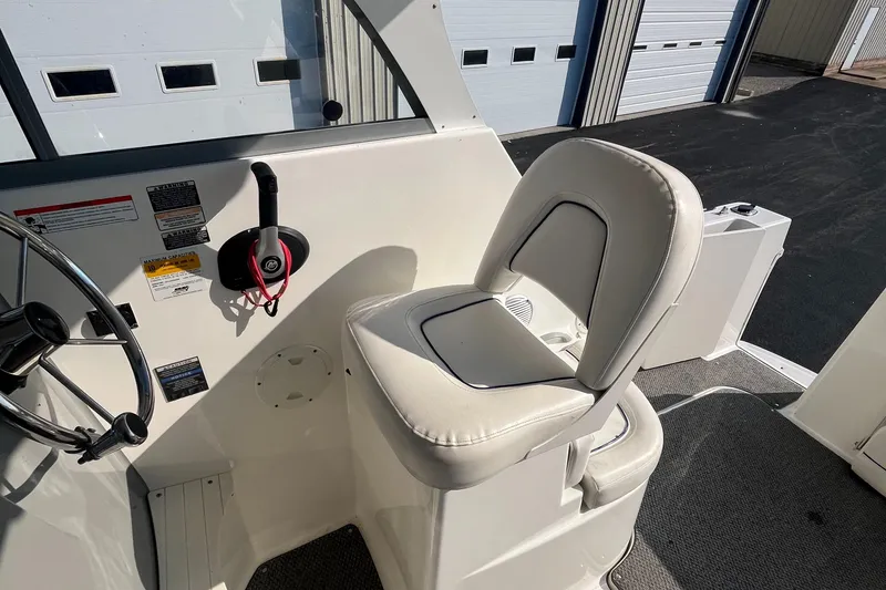 Slide: The Image of 2011 Bayliner 266 Discovery helm seat and controls in a marina setting. - 12