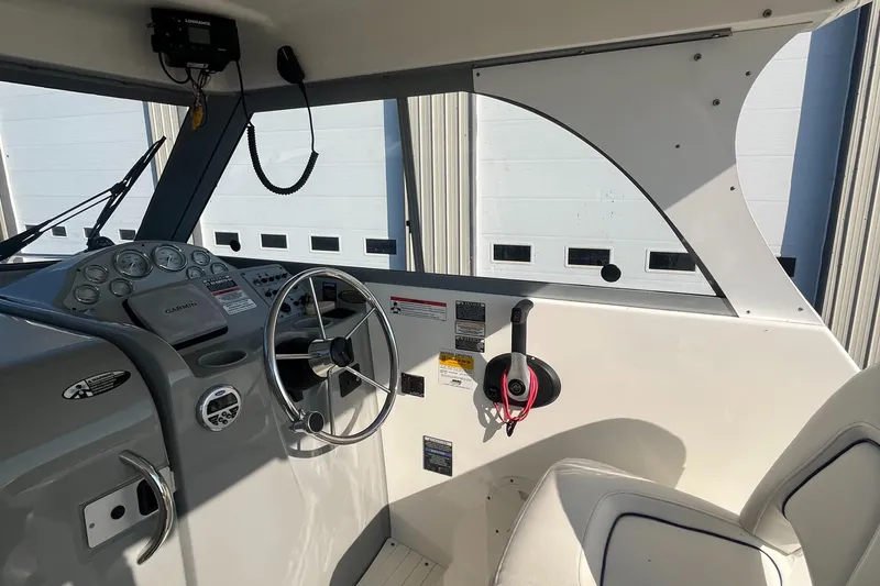 Slide: The Image of 2011 Bayliner 266 Discovery boat cockpit with steering wheel and control panel. - 13