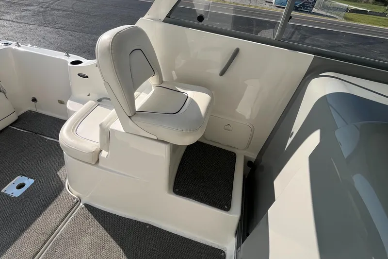 Slide: The Image of 2011 Bayliner 266 Discovery boat interior with white seating and carpeted flooring. - 16