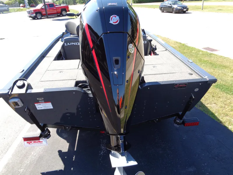 Slide: The Image of 2025 Lund 1875 Pro-V Bass XS boat with powerful outboard motor, parked on pavement. - 14