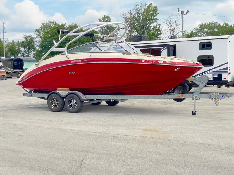 Slide: The Image of 2014 Yamaha Boats 242 Limited S in red on a trailer, parked outdoors. - 3