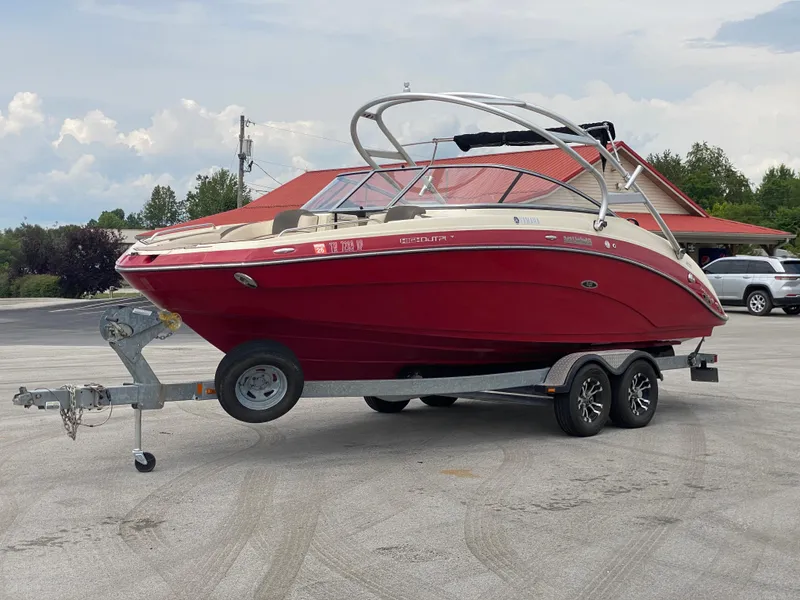 Slide: The Image of 2014 Yamaha Boats 242 Limited S on trailer, red hull, parked outdoors. - 39