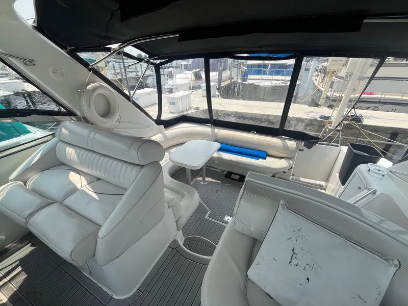 Slide: The Image of 2001 Cruisers Yachts 3870 Express interior with white seating and marina view. - 16