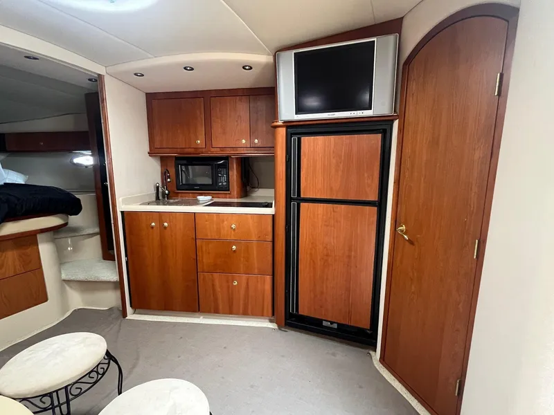 Slide: The Image of 2001 Cruisers Yachts 3870 Express interior with kitchenette, TV, and wood cabinetry. - 26