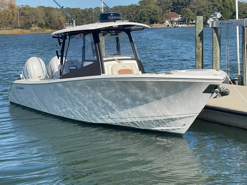 Slide: The Image of 2023 Cobia 320 CC boat docked on a sunny day. - 0