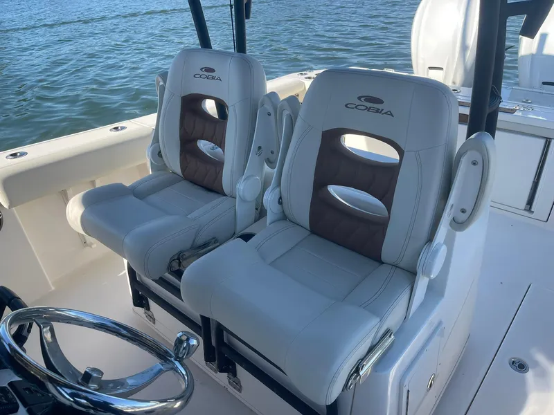 Slide: The Image of 2023 Cobia 320 CC boat seats with steering wheel, on calm water. - 10