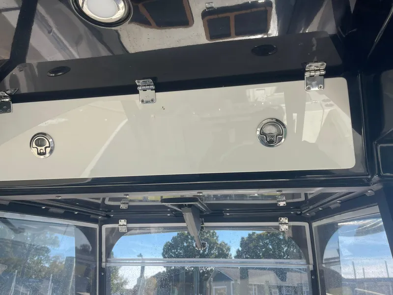Slide: The Image of 2023 Cobia 320 CC boat interior with storage compartments and latches. - 13
