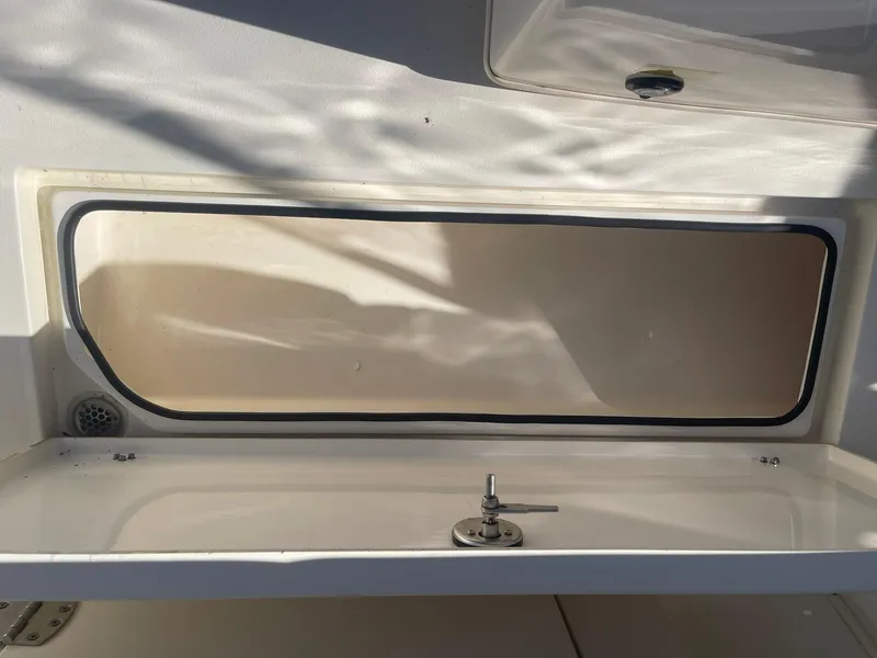 Slide: The Image of 2023 Cobia 320 CC boat storage compartment with latch, interior view. - 16